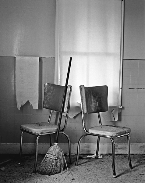 Interior with two chairs and sweeping brush. - Abandoned America