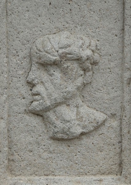 Façade portal, right pillar base relief (inner right) - San Juan Bautista, façade, portería & posa chapels