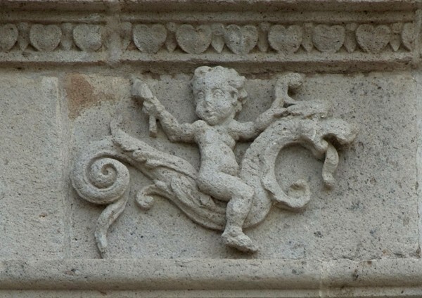 Façade architrave relief, putto aloft hippocamp - San Juan Bautista, façade, portería & posa chapels