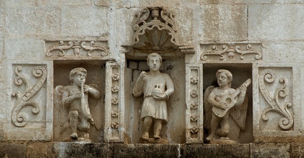 Façade cornice, niche sculptures - Façade, exterior buttressing, lateral portal, open & posa chapels, atrio & cross