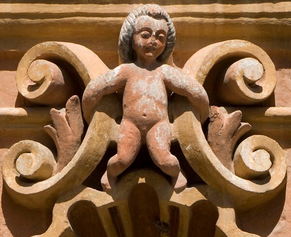 La Tercera Orden, façade, lower story niche relief, putto - Façade, lateral portal & sacristy door