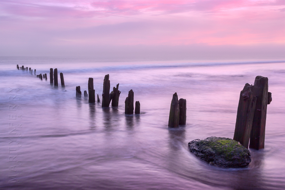 Beautiful image of beach groynes at sunrise in North Yorkshire