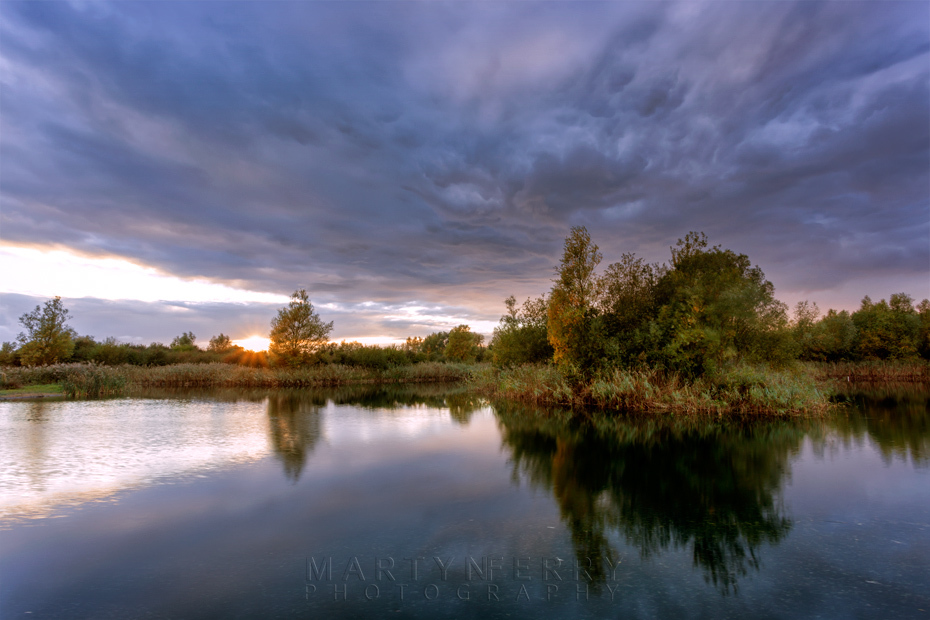 Storm clouds over a lake at Ouse Fen