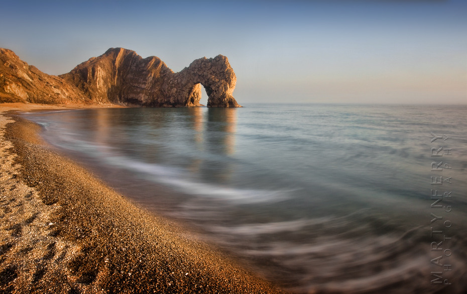 Classic sunset image of Durdle Door with long exposure