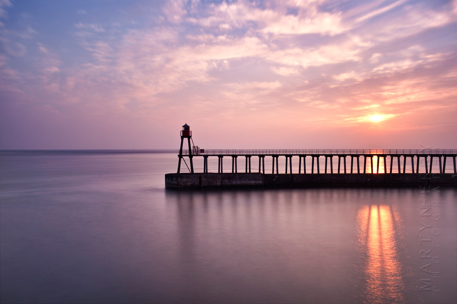 Vibrant sunrise reflection through Whitby pier