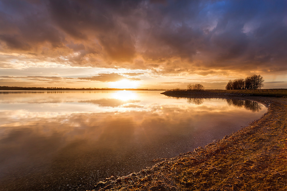 Setting sun on the horizon at Grafham Water reservoir