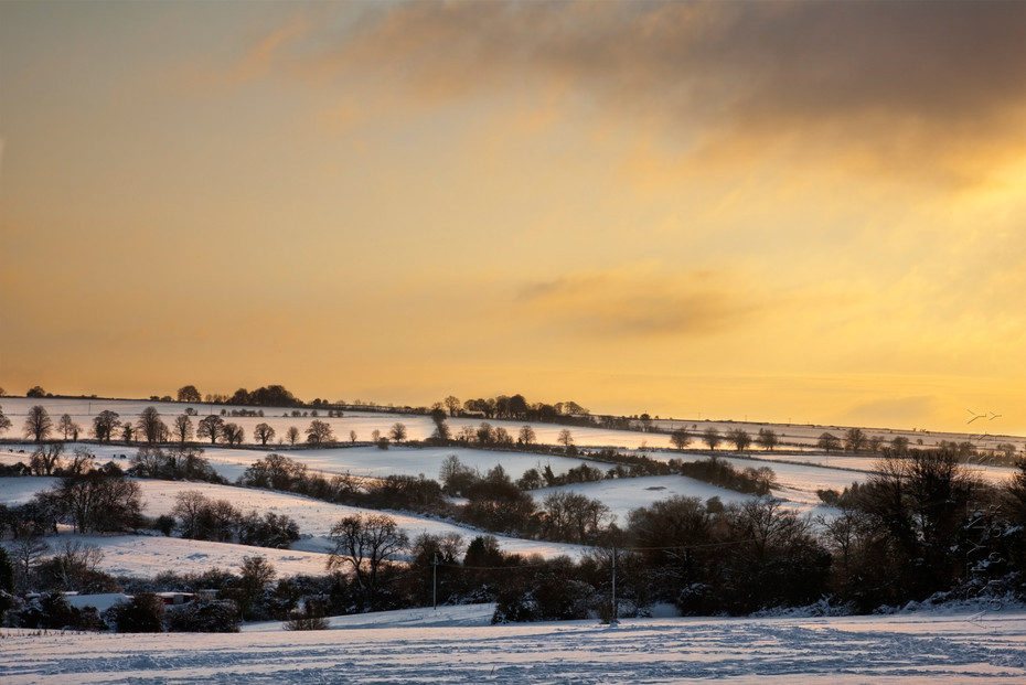 Stunning landscape view of a snowy Cotswold scene at sunset