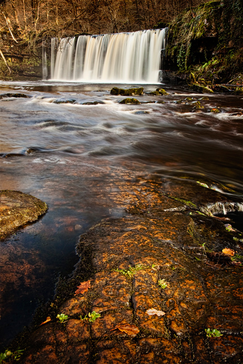 Autumn image of Welsh waterfall and river rocks