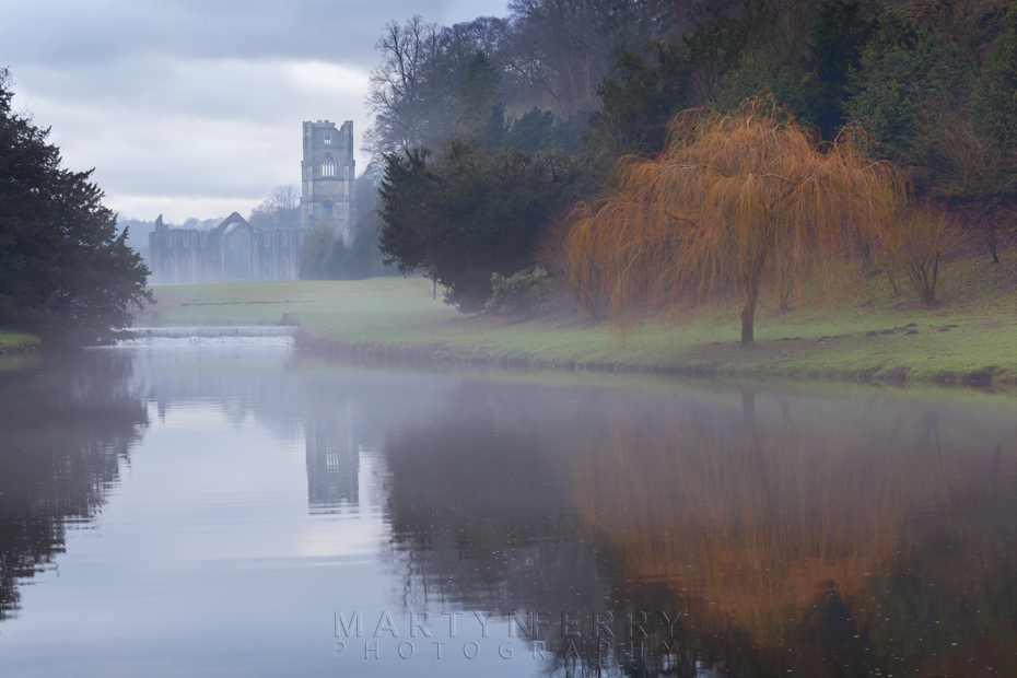 Mist over the lake with Fountains Abbey in the distance