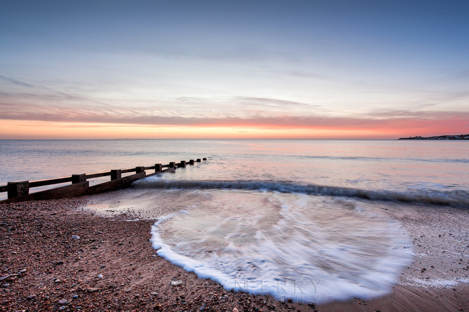 Waves spread over Swanage beach in Dorset at sunrise