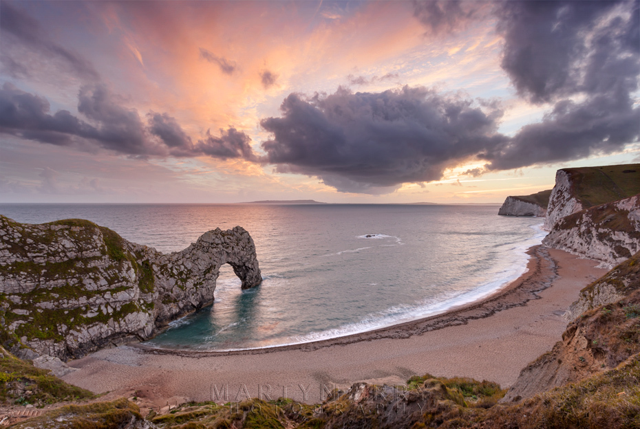 Sunset colours the clouds over Durdle Door