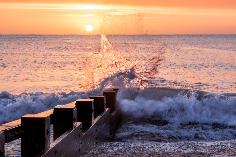 Splashing waves lit by the sunrise light on Swanage beach