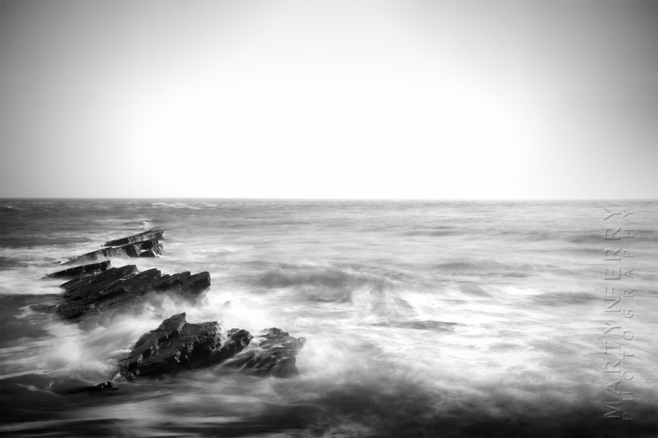Black and white photograph of waves crashing off the Dorset coast