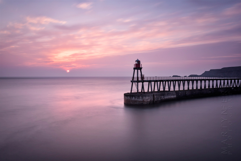 Colourful sunrise image of Whitby pier in North Yorkshire