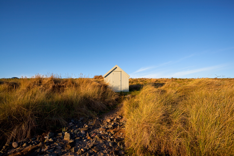 Morning sunshine at Bamburgh on a solitary beach hut