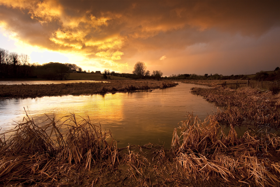 Image of warm sunset of a stormy evening over cotswolds river