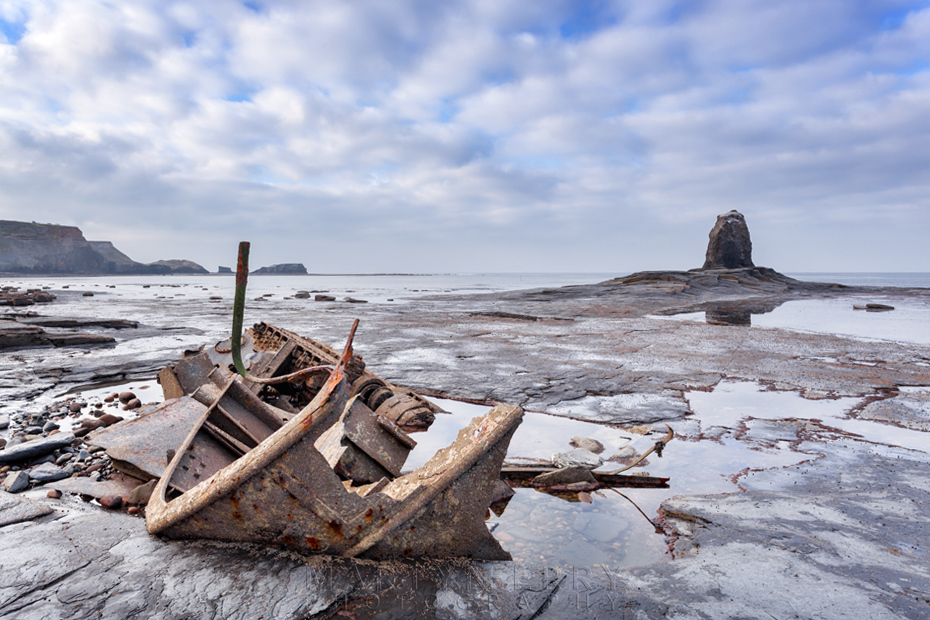 Saltwick Bay shipwreck with Black Nab under fluffy clouds