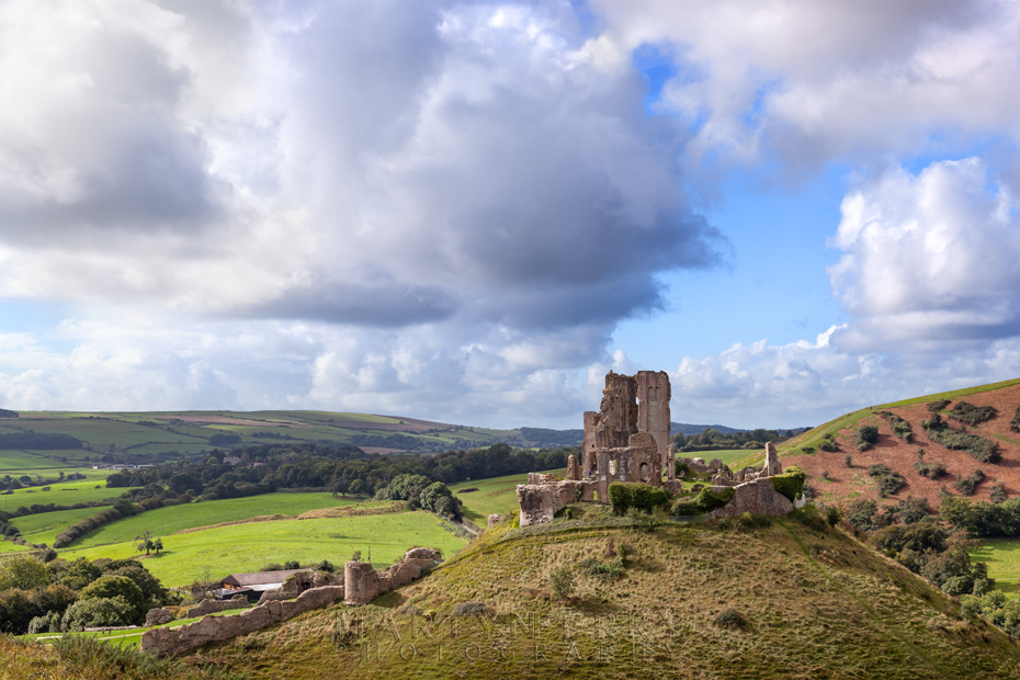 Corfe Castle in the morning sun under fluffy clouds