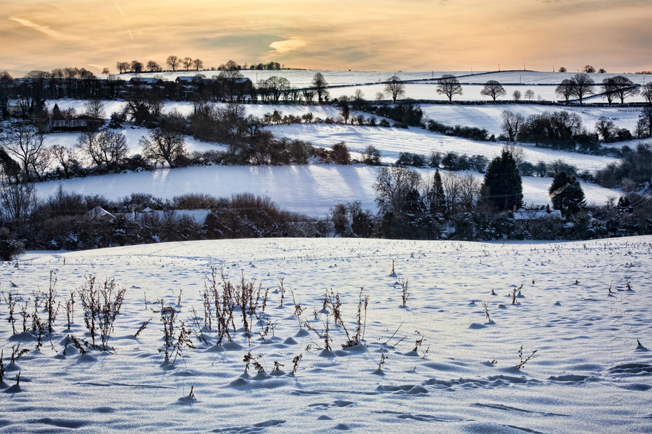 Winter landscape photograph of Chipping Norton hill under snow at sunset