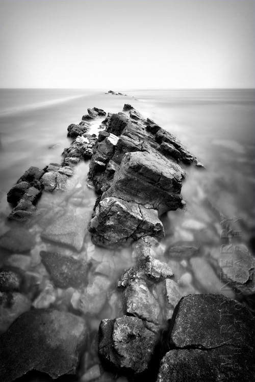 Beautiful black and white image of dramatic rocks in a smooth ocean