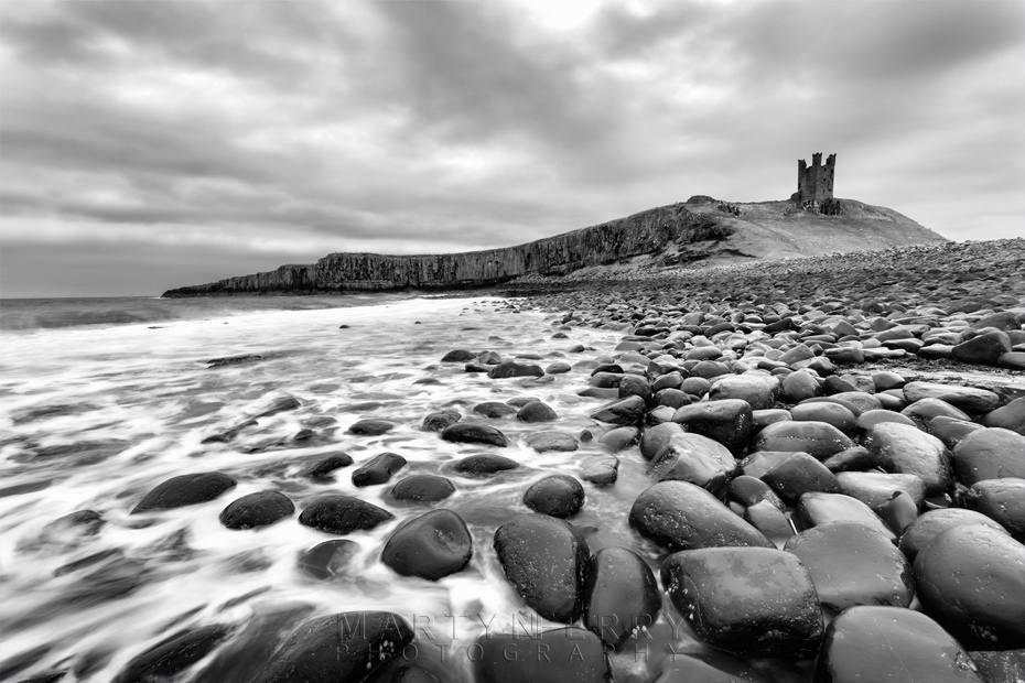 Dunstanburgh Castle under stormy clouds