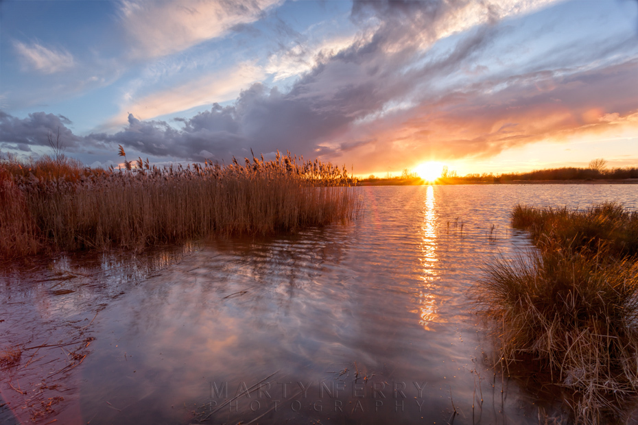 Bright sunset beams beneath the clouds at Ouse Fen Nature Reserve