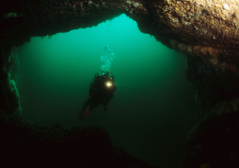 Diver explores natural arch - Diver exploring marine environment